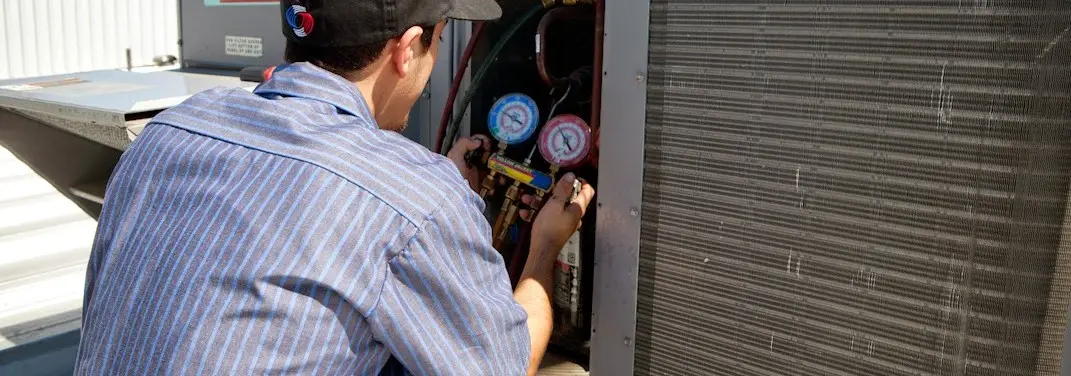 HVAC technician servicing a condenser unit in Hollister