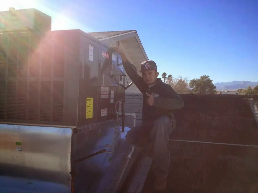 HVAC technician performing AC Tune-Up on a rooftop unit in Hollister